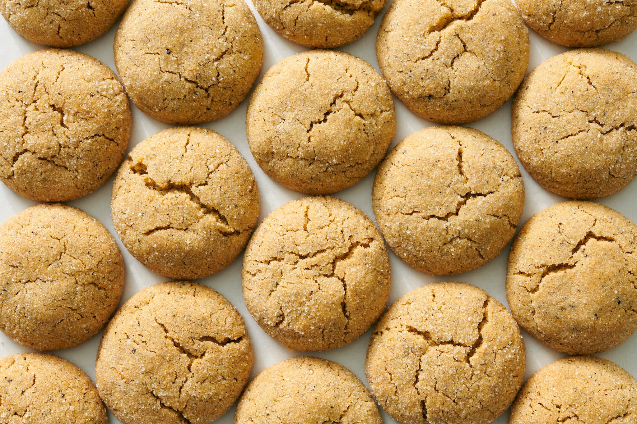 An overhead image of a batch of light-brown crinkled cookies.