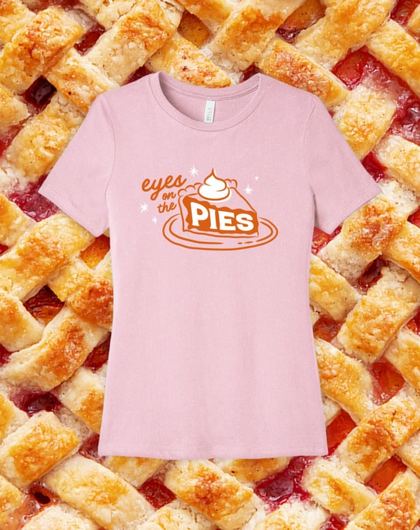Image of a pink tshirt reading "Eyes on the Pies" on a background of closeup lattice pie texture.