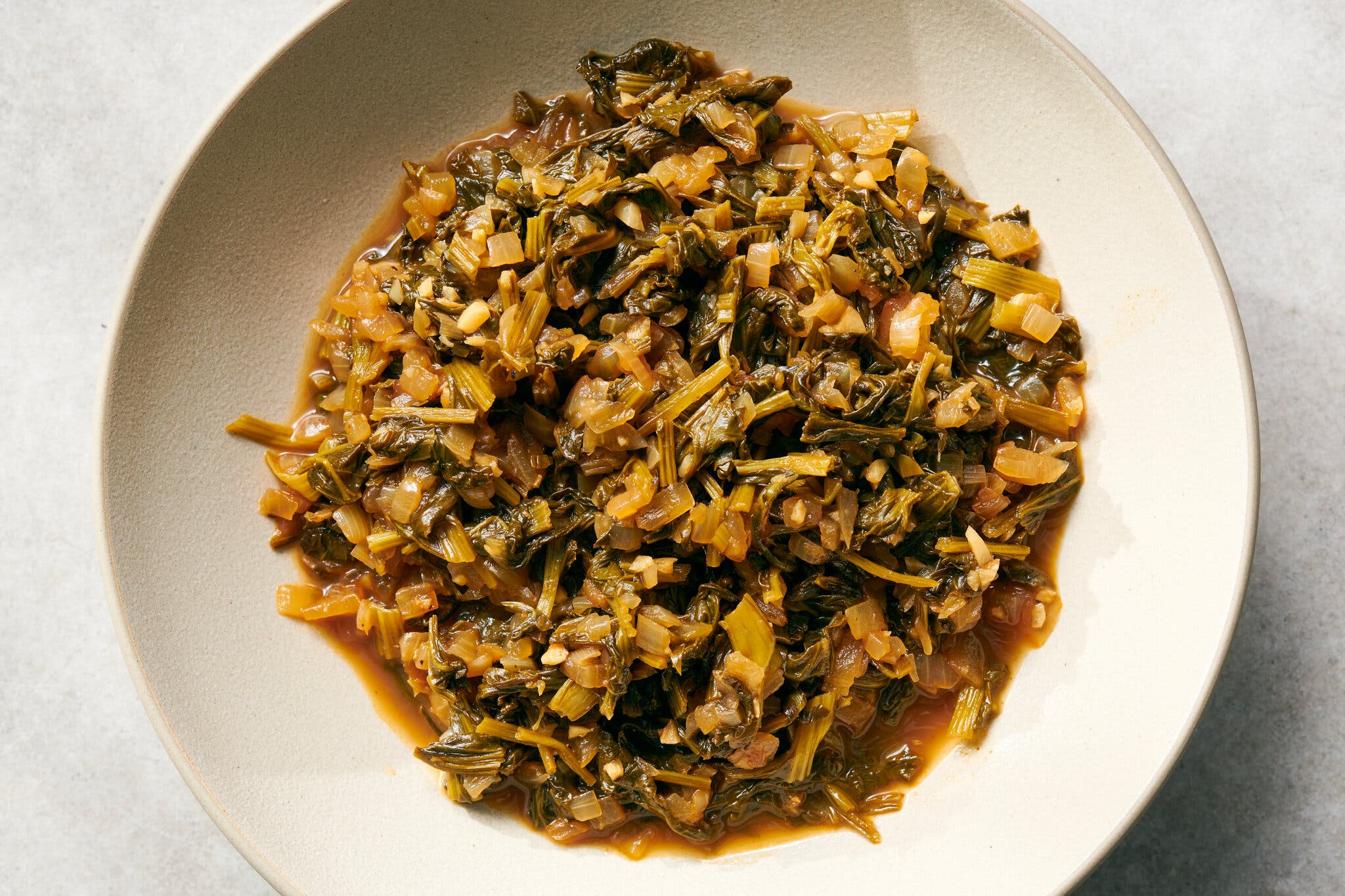 An overhead shot of a white bowl of turnip greens.